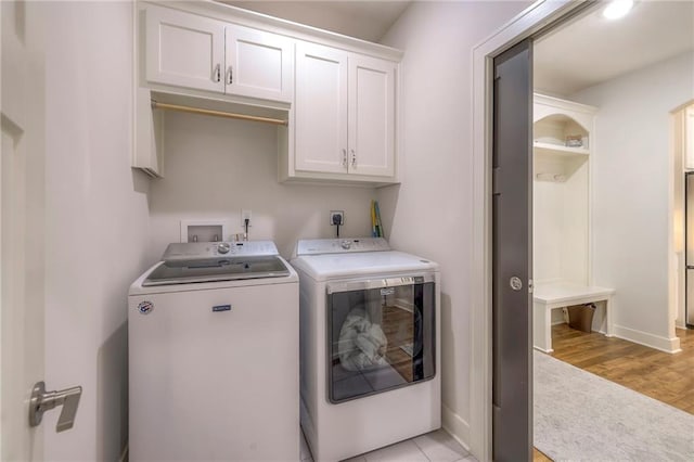 laundry area with light wood-type flooring, cabinets, and washer and dryer