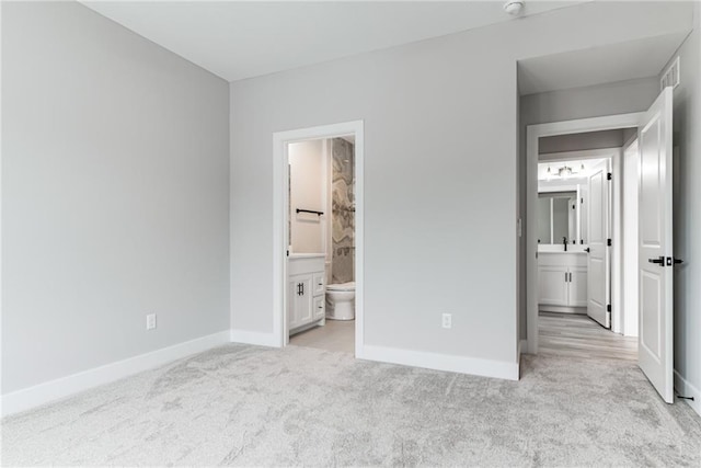 unfurnished bedroom with connected bathroom and light colored carpet