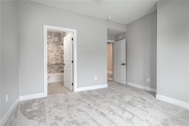 unfurnished bedroom featuring ensuite bathroom and light carpet