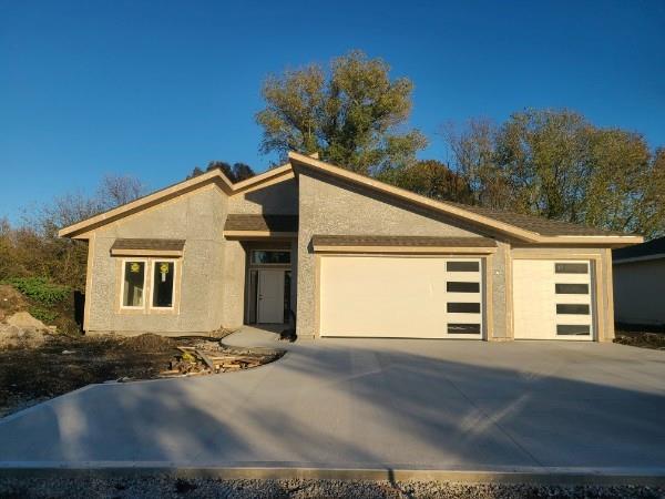 15903 S Lindenwood Dr, Olathe, KS 66062 - view of front of home with an attached garage, concrete driveway, and stucco siding