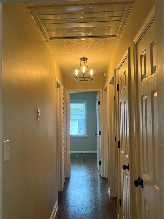 hall with dark hardwood / wood-style flooring, a chandelier, and a textured ceiling