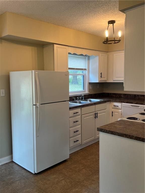 kitchen featuring pendant lighting, a textured ceiling, sink, white fridge, and white cabinetry