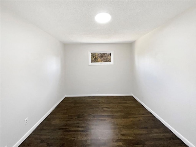 empty room with a textured ceiling and dark hardwood / wood-style floors