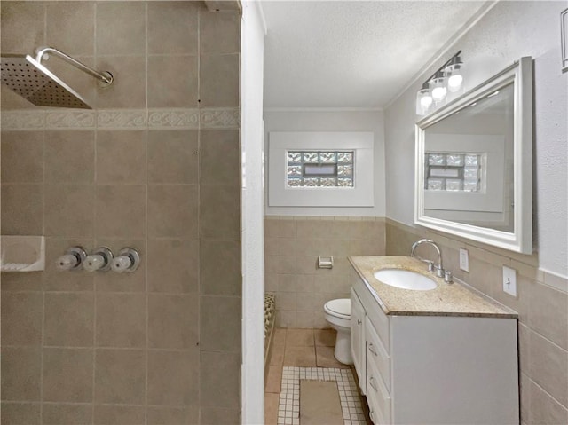 bathroom with tile walls, tile patterned flooring, tiled shower, and vanity