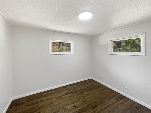 unfurnished room featuring dark wood-type flooring and a textured ceiling