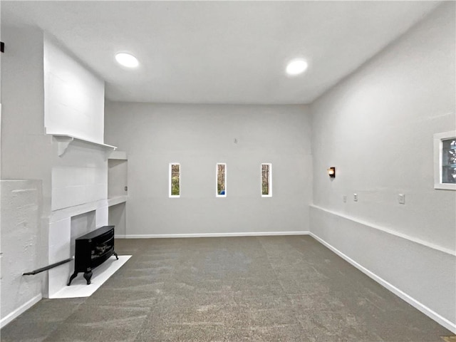 interior space with a wood stove and dark carpet