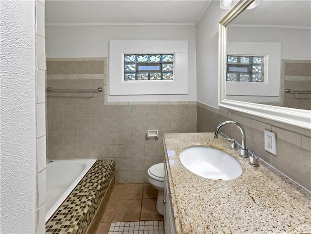 bathroom featuring vanity, a bath, tile patterned floors, toilet, and tile walls