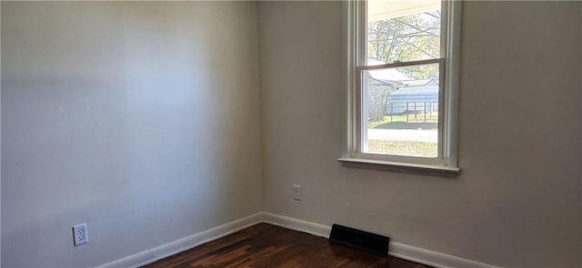 spare room featuring a wealth of natural light and dark hardwood / wood-style floors