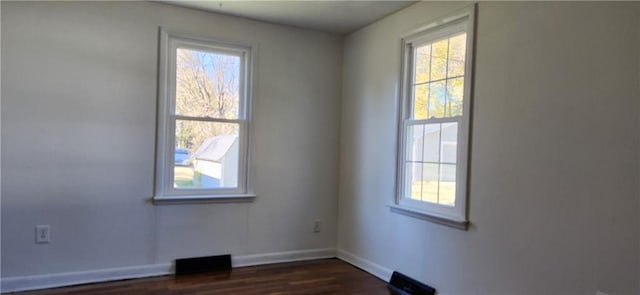 spare room with a wealth of natural light and dark hardwood / wood-style flooring