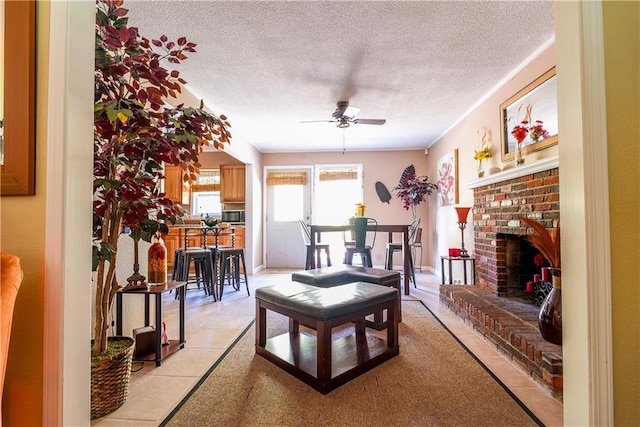 interior space featuring a fireplace, light tile patterned floors, a textured ceiling, and ceiling fan