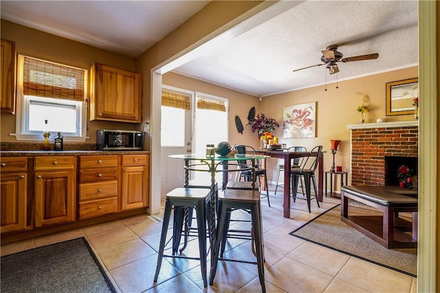 kitchen featuring a fireplace, light tile patterned floors, a textured ceiling, and ceiling fan