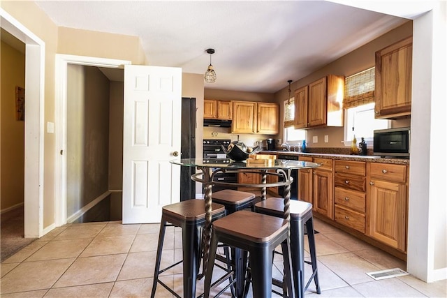 kitchen featuring black range, light tile patterned flooring, sink, and hanging light fixtures