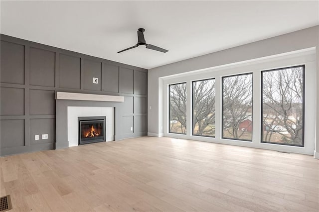 unfurnished living room featuring ceiling fan, a tiled fireplace, and light hardwood / wood-style floors