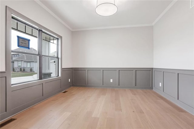 empty room with ornamental molding and light hardwood / wood-style flooring