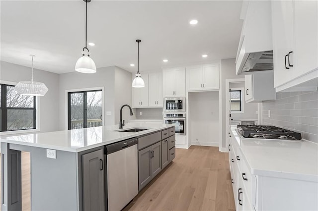 kitchen featuring gray cabinets, premium range hood, appliances with stainless steel finishes, white cabinetry, and a kitchen island with sink