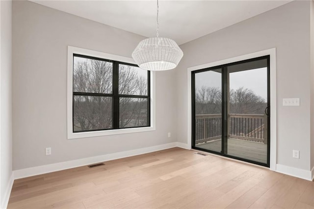 spare room with an inviting chandelier and light hardwood / wood-style flooring