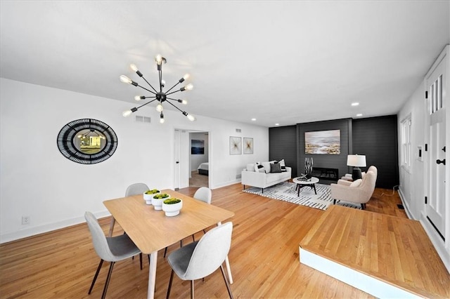 dining space featuring an inviting chandelier, light hardwood / wood-style floors, and a fireplace