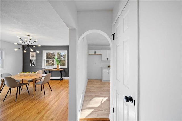 hall with an inviting chandelier and light hardwood / wood-style floors