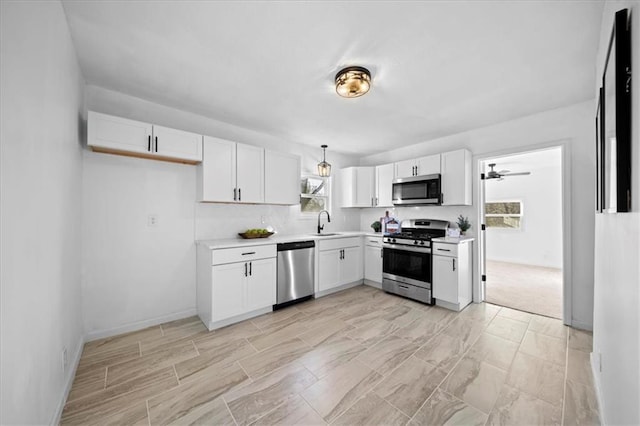 kitchen with stainless steel appliances, hanging light fixtures, white cabinetry, and sink