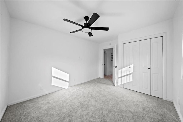 unfurnished bedroom featuring a closet, light colored carpet, and ceiling fan