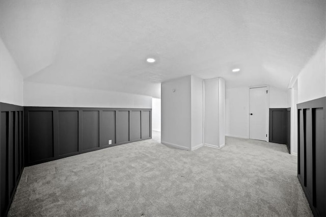 bonus room with light colored carpet and vaulted ceiling