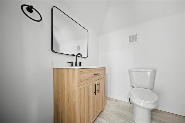 bathroom with wood-type flooring, vanity, toilet, and vaulted ceiling