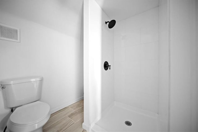 bathroom with toilet and a tile shower