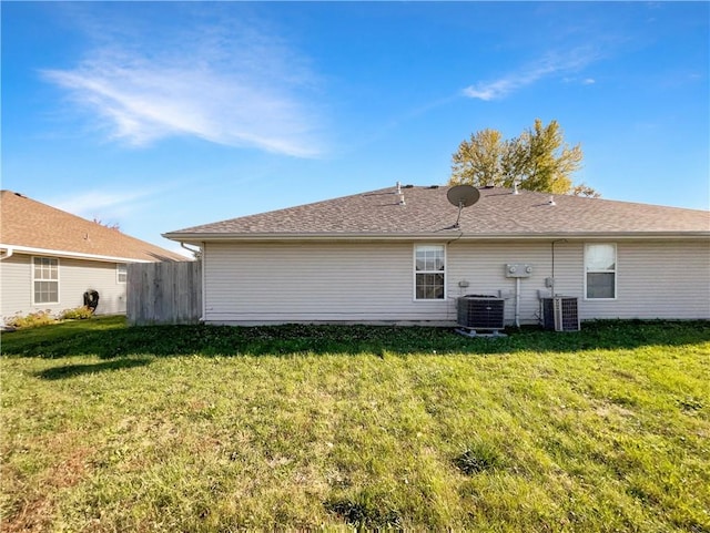 back of property with central AC unit and a yard