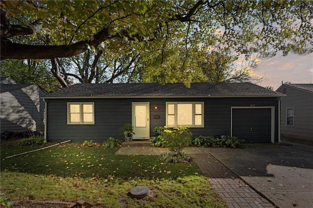 ranch-style home featuring a lawn and a garage