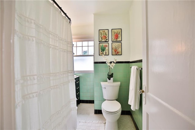 bathroom with tile walls, toilet, vanity, and tile patterned floors