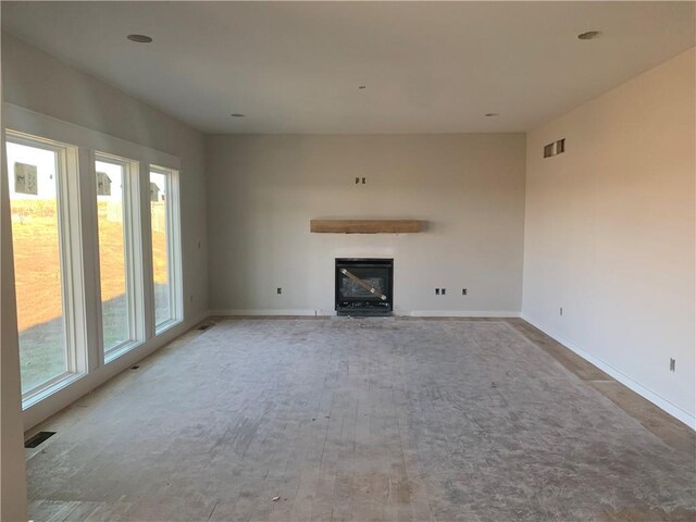 422 Victory Cir, Kearney, MO 64060 - unfurnished living room featuring a glass covered fireplace, baseboards, and wood finished floors