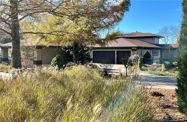 view of front of property featuring concrete driveway, an attached garage, and stucco siding