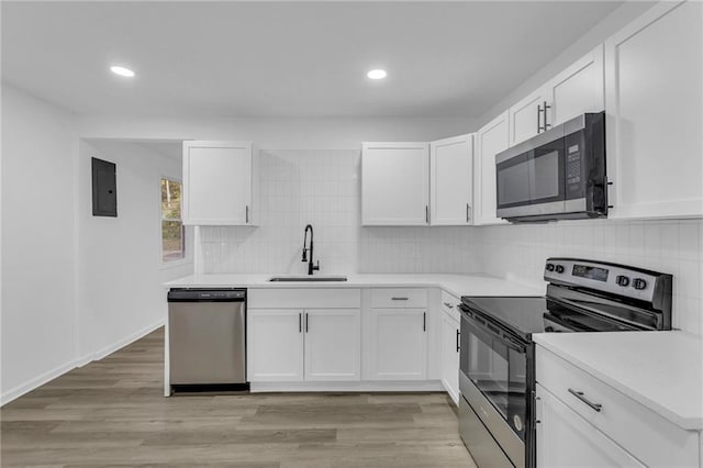 kitchen with electric panel, light hardwood / wood-style floors, stainless steel appliances, sink, and white cabinetry