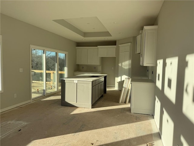 kitchen with a raised ceiling, a center island, and white cabinets