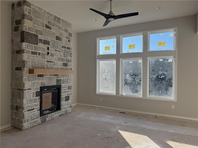 unfurnished living room featuring a stone fireplace and ceiling fan