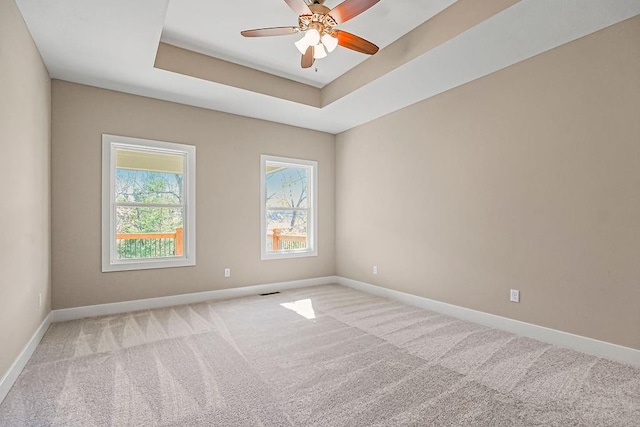 spare room with baseboards, a raised ceiling, carpet, and a ceiling fan