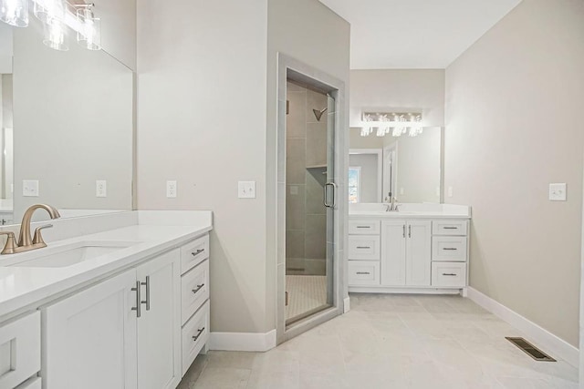 bathroom with visible vents, a shower stall, baseboards, two vanities, and a sink