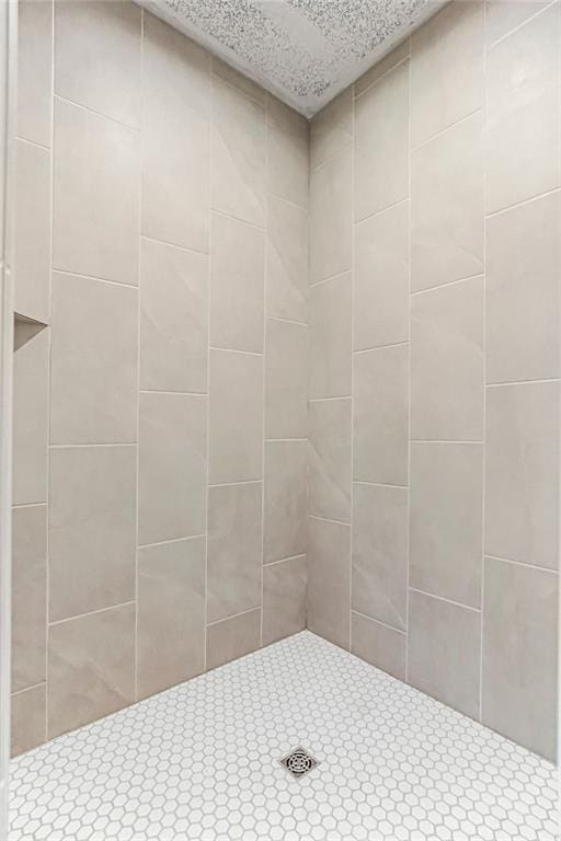 full bath with a textured ceiling and tiled shower