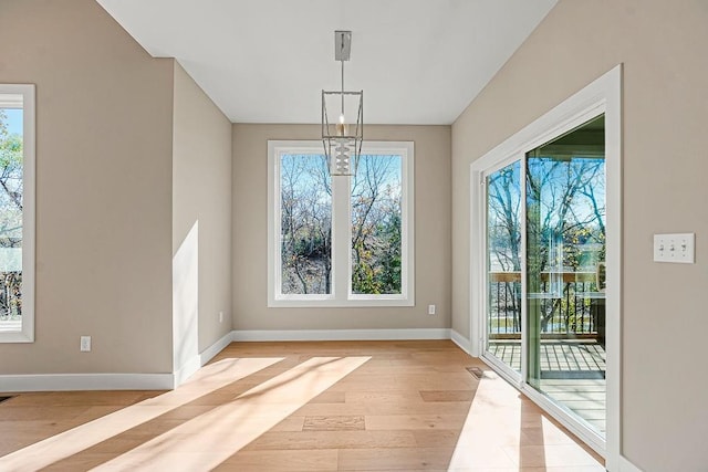 unfurnished dining area featuring visible vents, a healthy amount of sunlight, baseboards, and light wood-style floors