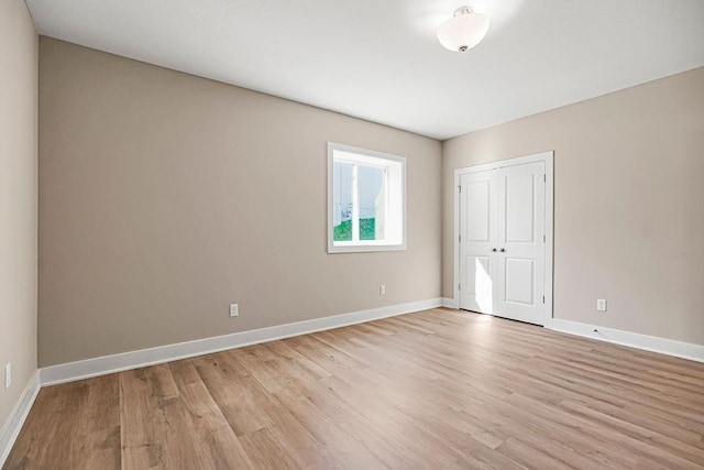 unfurnished bedroom featuring baseboards, light wood-type flooring, and a closet