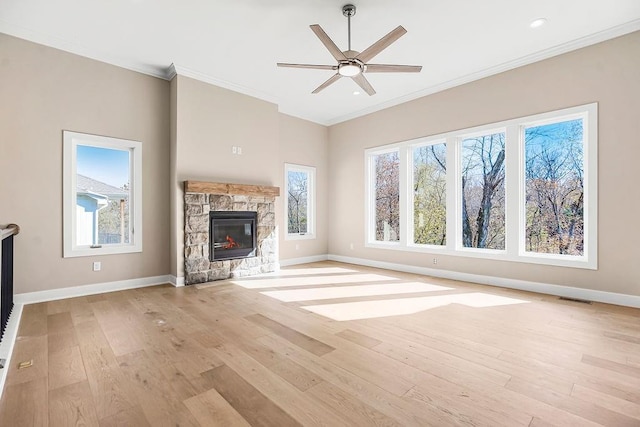 unfurnished living room with visible vents, crown molding, baseboards, light wood-type flooring, and a stone fireplace