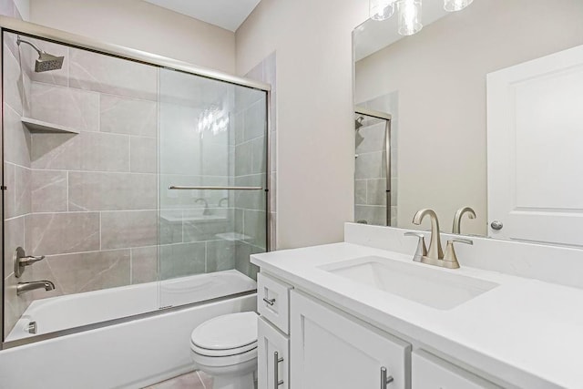 full bath with vanity, toilet, and bath / shower combo with glass door