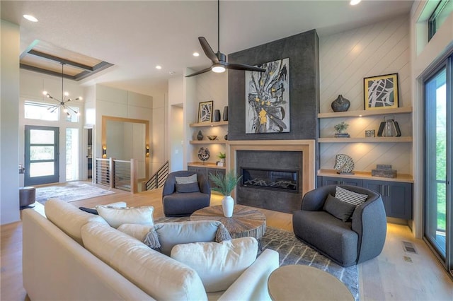 living room with a large fireplace, a healthy amount of sunlight, light wood-type flooring, and built in features