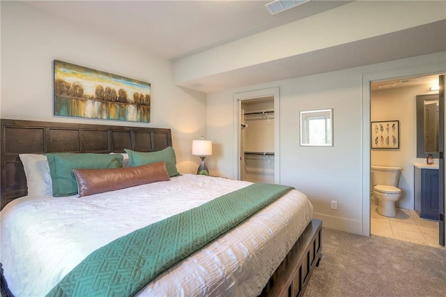 bedroom featuring light colored carpet, a spacious closet, connected bathroom, and a closet