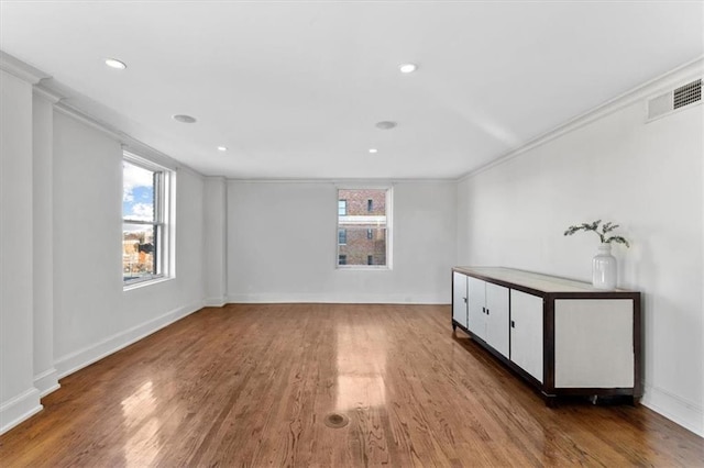 spare room with hardwood / wood-style floors, ornamental molding, and a healthy amount of sunlight