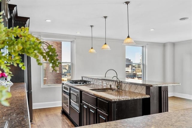 kitchen with a kitchen breakfast bar, sink, light hardwood / wood-style flooring, an island with sink, and decorative light fixtures