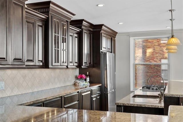 kitchen featuring stainless steel fridge, dark brown cabinetry, and decorative light fixtures