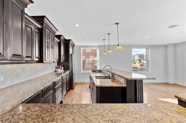 kitchen featuring plenty of natural light, an island with sink, hanging light fixtures, and light hardwood / wood-style floors