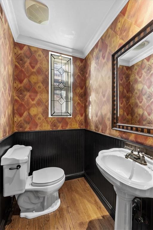 bathroom featuring hardwood / wood-style flooring, toilet, ornamental molding, and sink