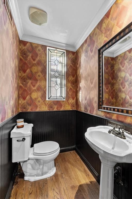 bathroom featuring wood-type flooring, toilet, and ornamental molding